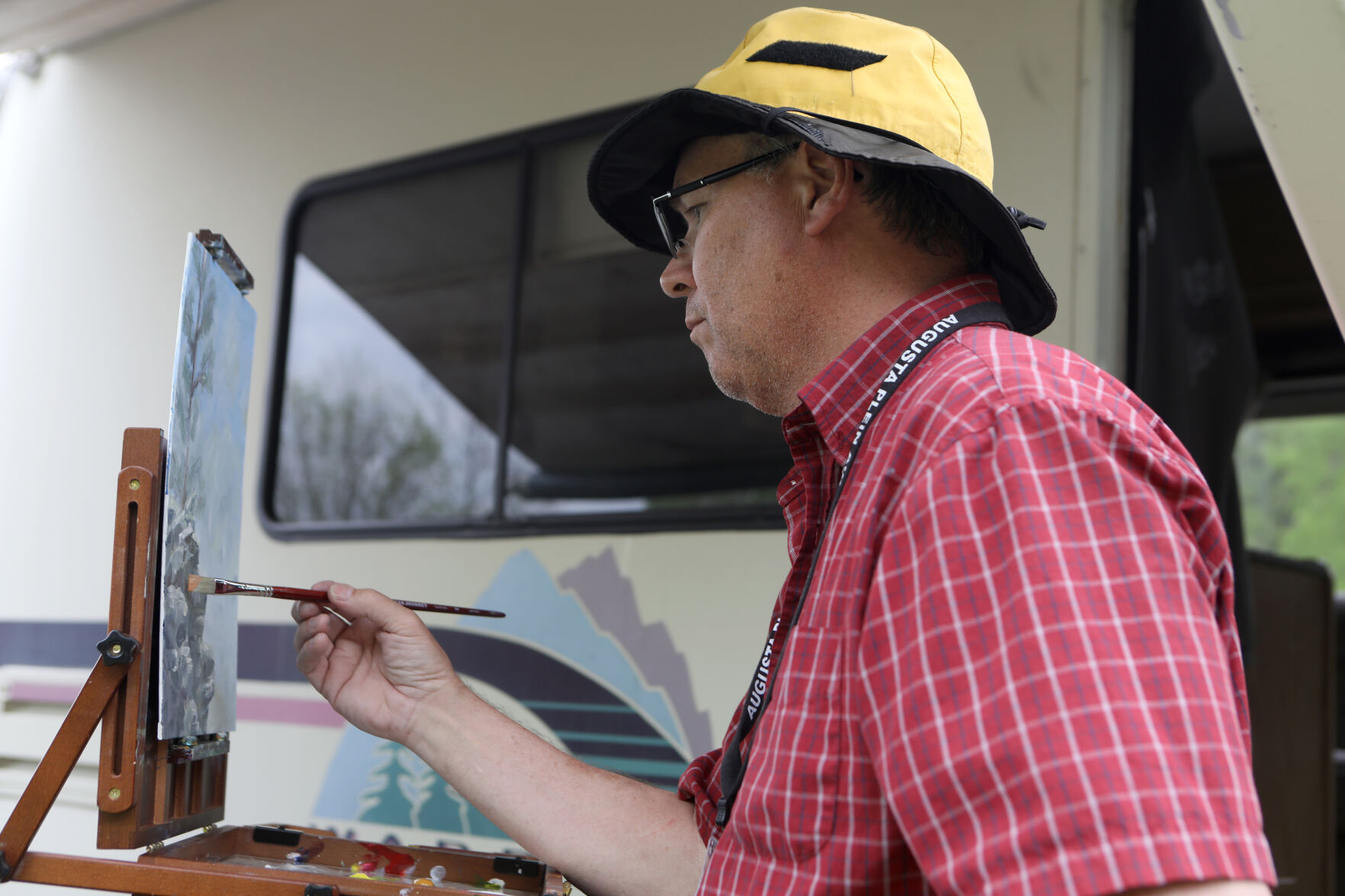 Jamie Green paints under an RV awning